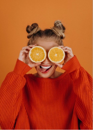 Sophie smiling and holding orange slices over her eyes