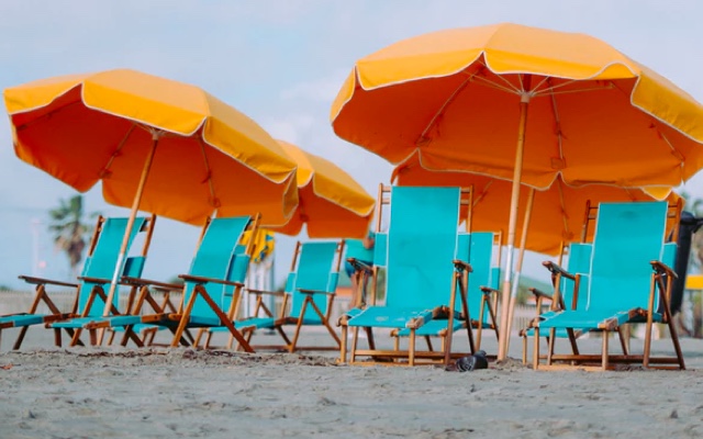 blue chairs on a beach with orange umbrellas