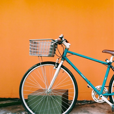 blue bike with basket infront of a orange wall